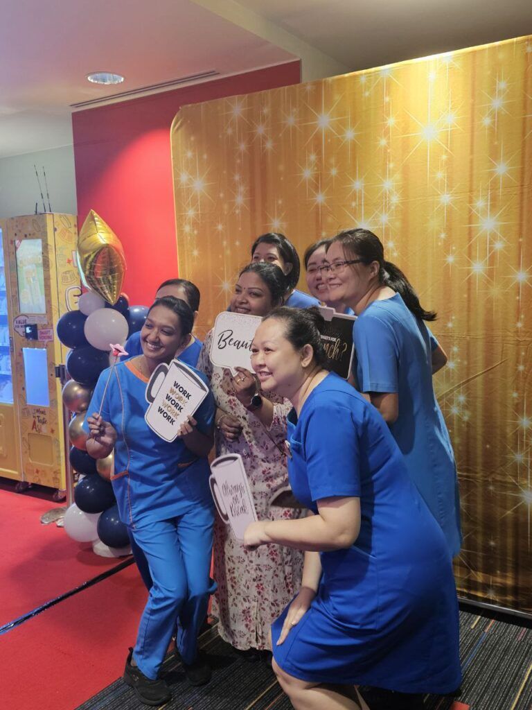 Nurses at the photo booth with props and a gold backdrop